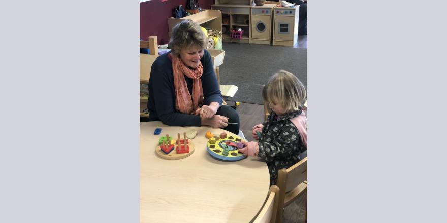 Teacher and child playing with blocks at preschool