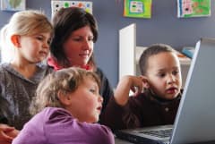 Teacher and kids using the computer at preschool 